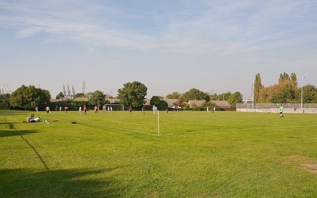 A soccer field with players, goalposts, and a clear sky.