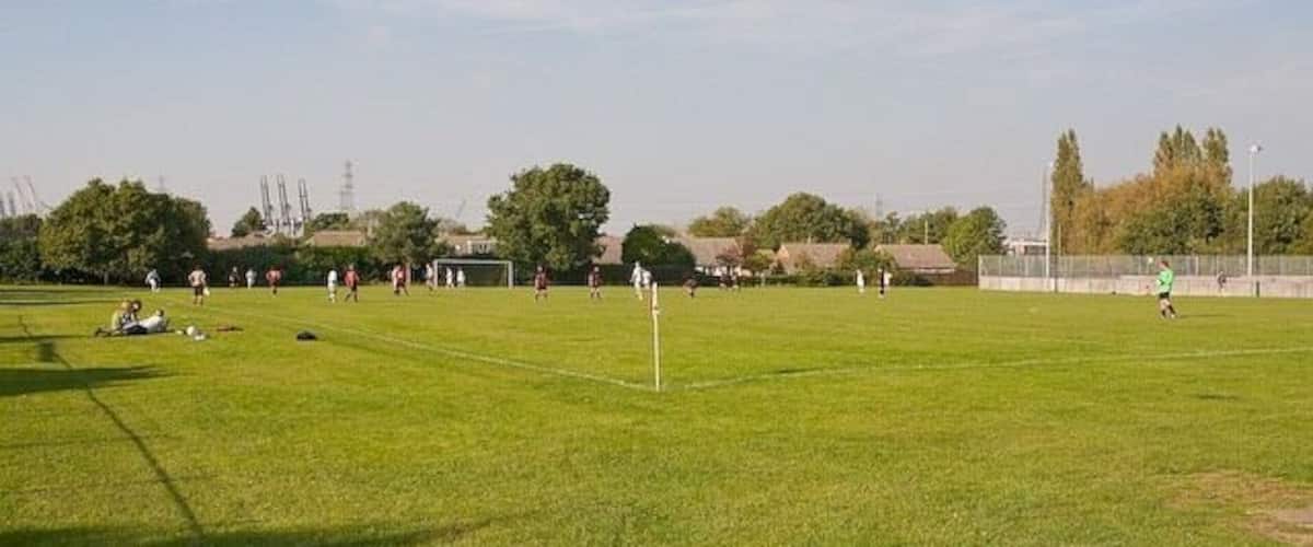 A soccer field with players, goalposts, and a clear sky.