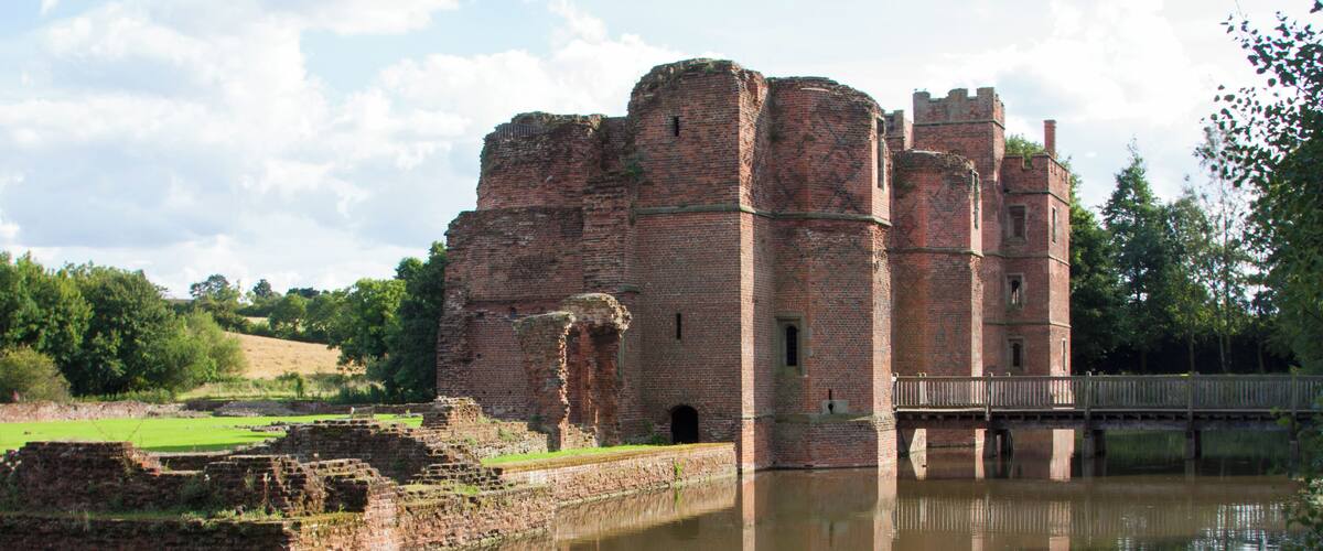 A historic castle with a moat and a wooden bridge.