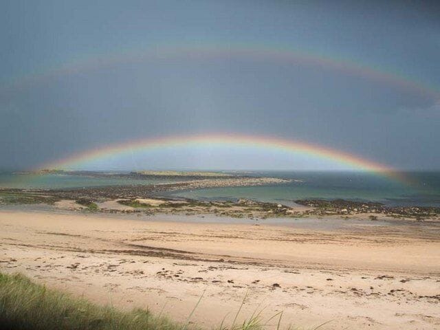 A beach with a rainbow over the water.