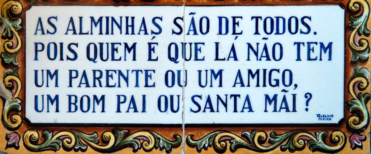 A decorative sign with ornate borders and text in Portuguese.