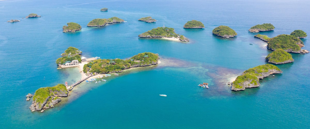 An aerial view of a chain of lush green islands surrounded by turquoise waters.