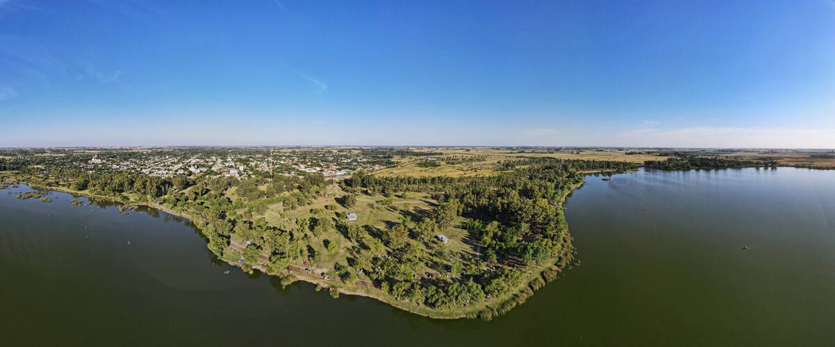 An aerial view of a large island with dense forests, a small town, and a calm lake.