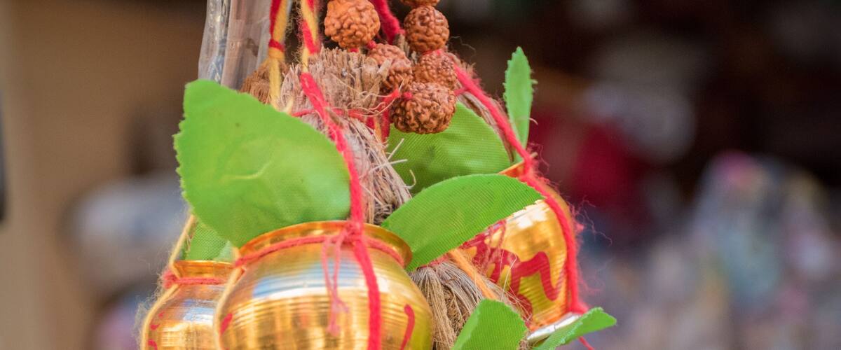 A traditional hanging ornament with brass containers, red strings, and decorative elements.