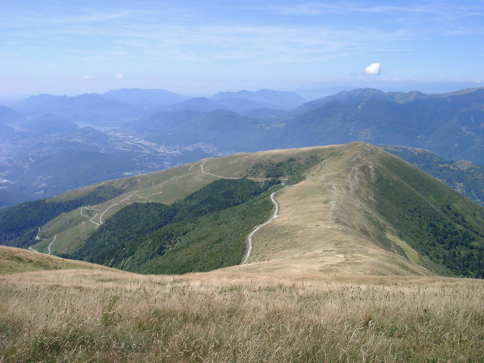 A mountain landscape with a winding road and dense forest areas.