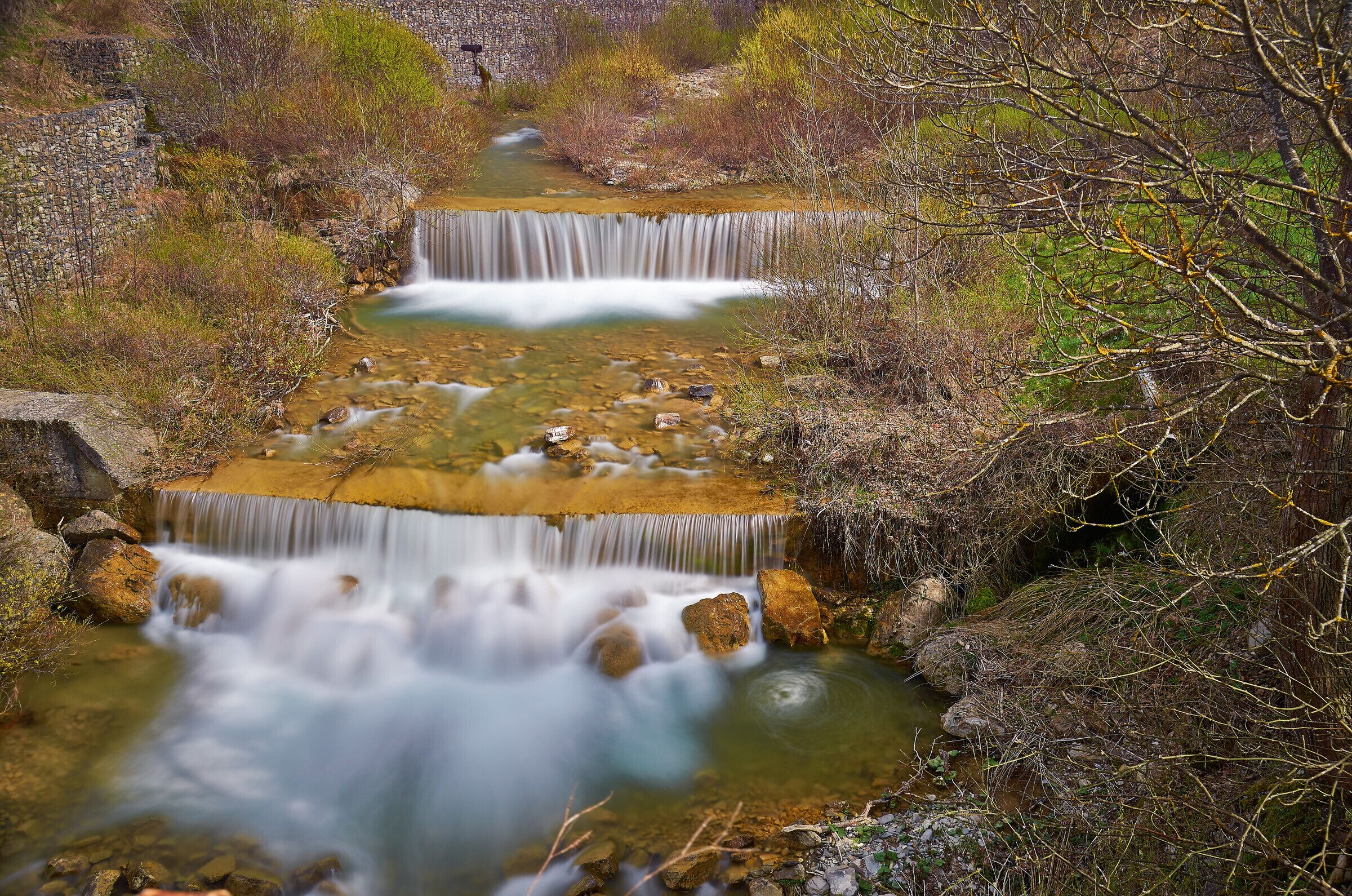 A waterfall cascading over rocks in a forested area.