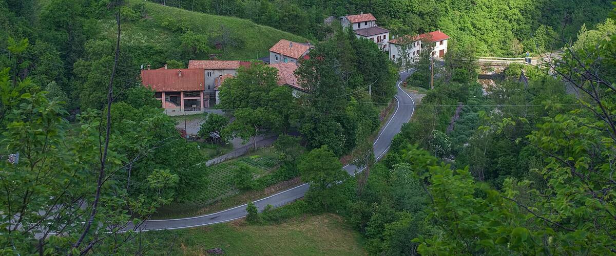 Eine kurvenreiche Straße durch ein üppiges, grünes Tal mit mehreren Häusern und Gebäuden.
