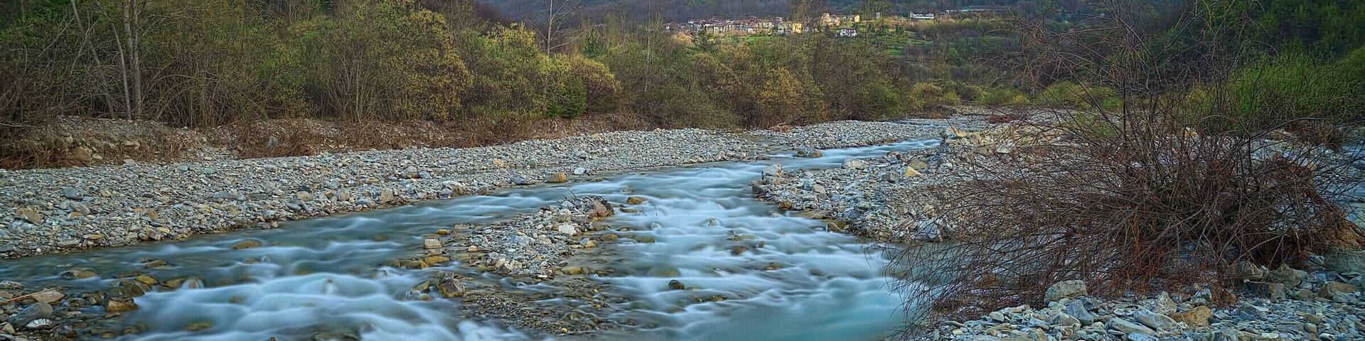 A river flowing through a rocky landscape with mountains in the background.