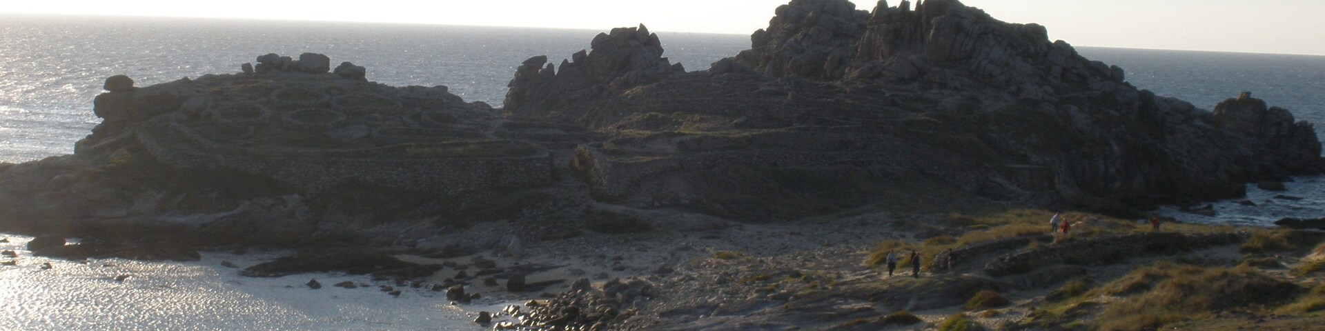 Paisaje costero con acantilados rocosos y una playa.