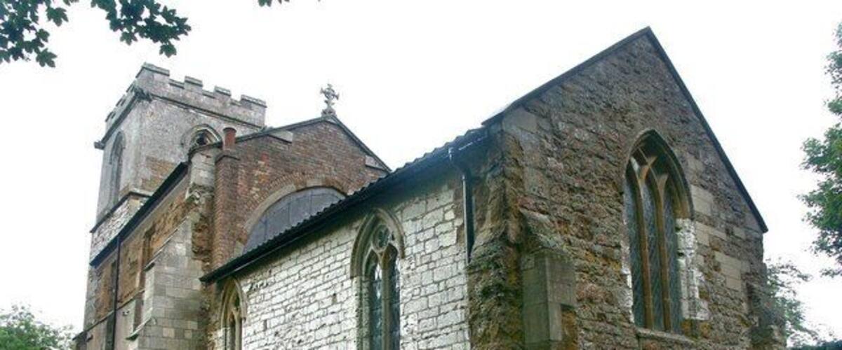 A stone church with a bell tower and two large arched windows.