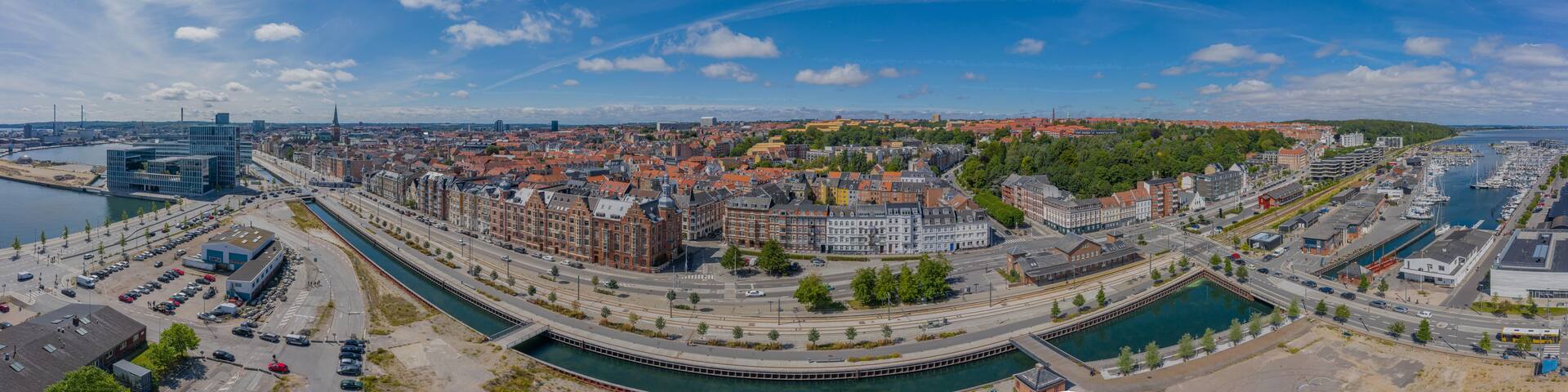 A panoramic view of a city with a river, historic buildings, and modern architecture.