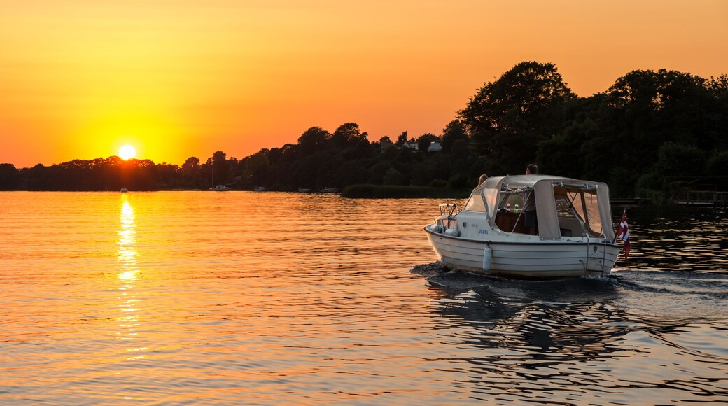 Un bateau sur une eau calme, au coucher du soleil, avec un ciel dégagé.