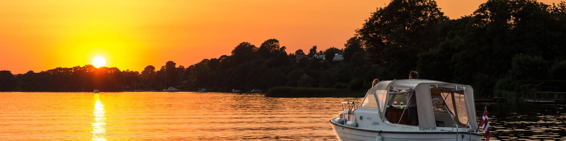 A boat on calm water during sunset with a clear sky.