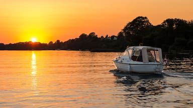 Un barco sobre aguas tranquilas durante la puesta de sol, con cielo despejado.