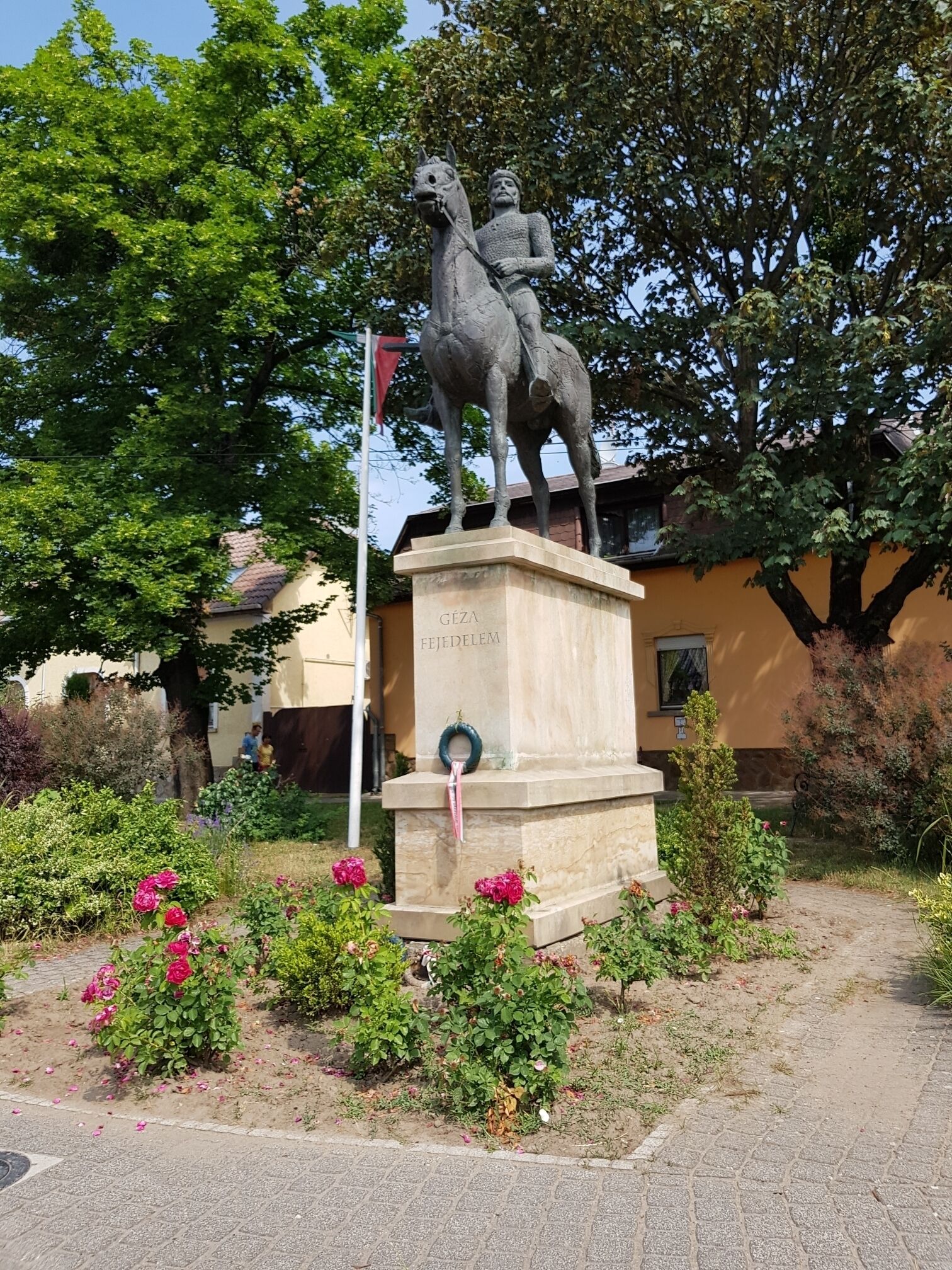 A statue of a man on horseback, surrounded by greenery and flowers.
