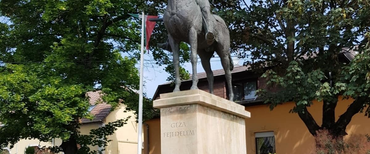 A statue of a man on horseback, surrounded by greenery and flowers.