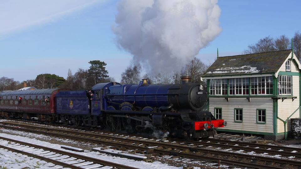 A steam locomotive with the number 6023 pulling a passenger train.