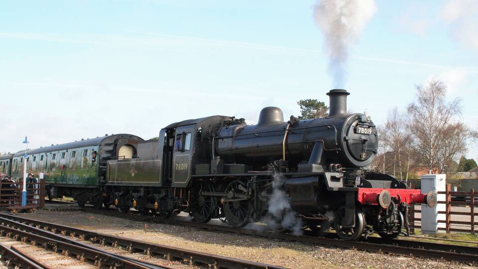 A steam locomotive numbered 78019 on tracks with a passenger car.