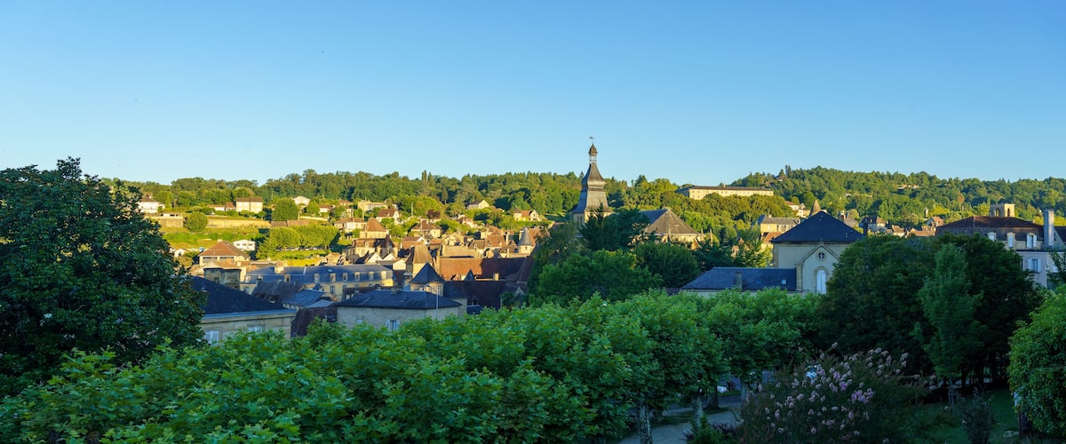 A town with historic buildings, a prominent church tower, and lush greenery.