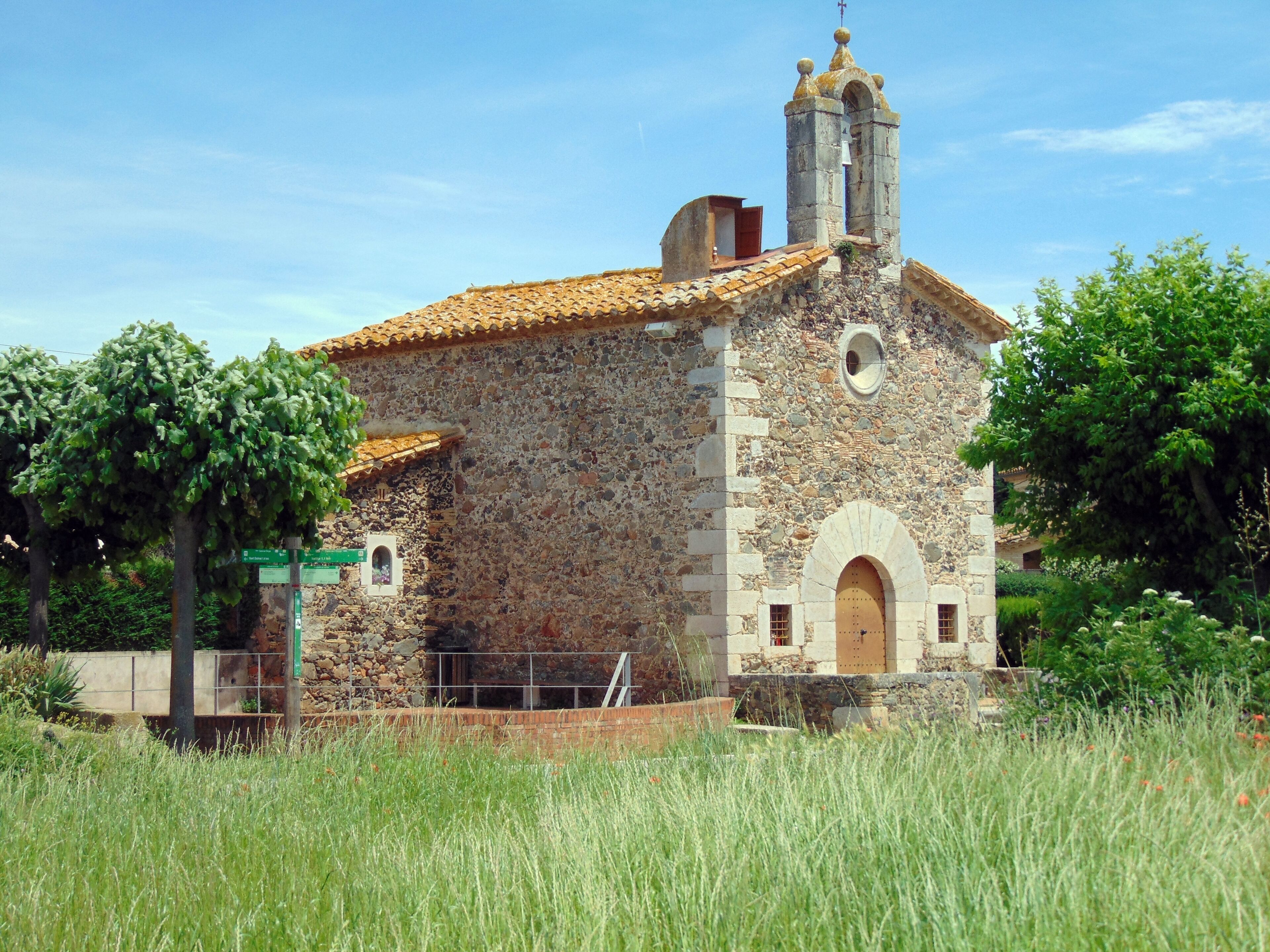 A stone church with a bell tower and a tiled roof.