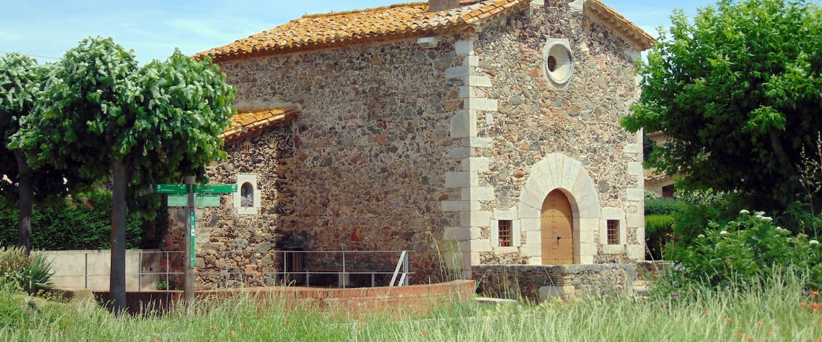 A stone church with a bell tower and a tiled roof.