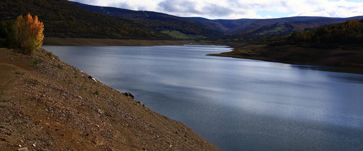Un lago tranquilo rodeado de colinas con follaje otoñal.