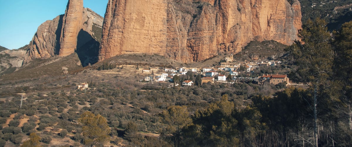 A mountainous landscape with prominent rock formations and a small village nestled at the base.