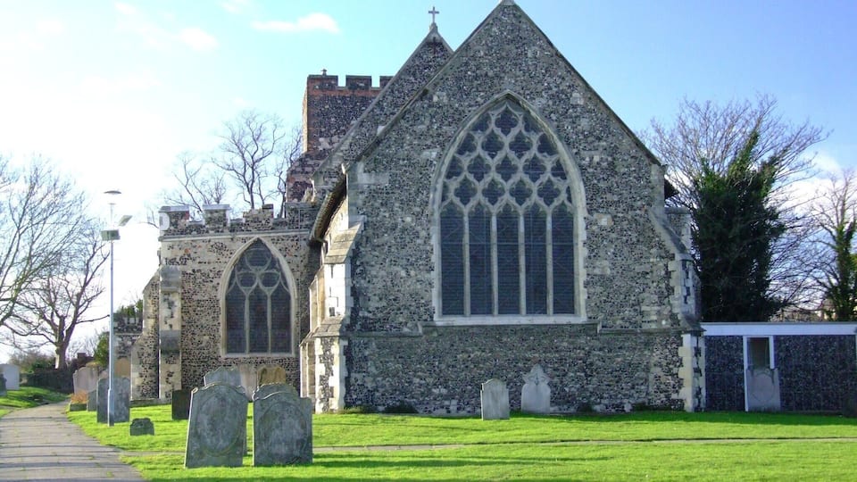 A historic church with a large arched window and a cross on top.