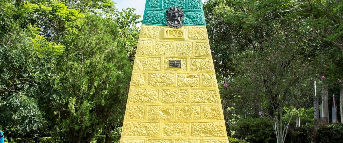 Een groot, kleurrijk obeliskmonument omringd door weelderige begroeiing.