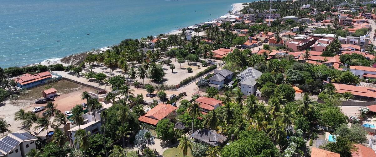 A coastal town with a beach, palm trees, and red-roofed buildings.