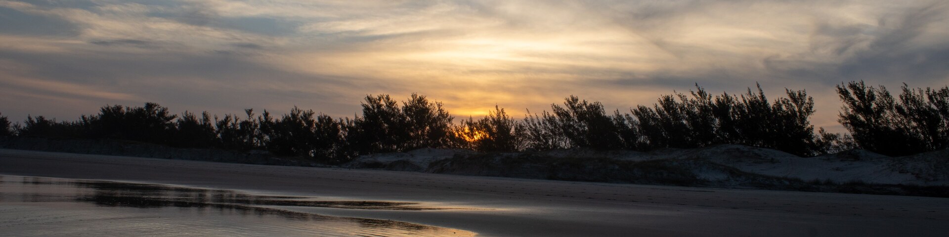 Pôr do sol na praia Village Dunas em Balneário Gaivota, Santa Catarina, Brasil. Capturado durante uma viagem de fim de semana pela praia. Núvens em formato de x.