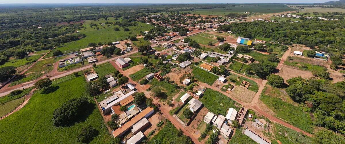An aerial view of a rural town with scattered houses, green fields, and a soccer field.