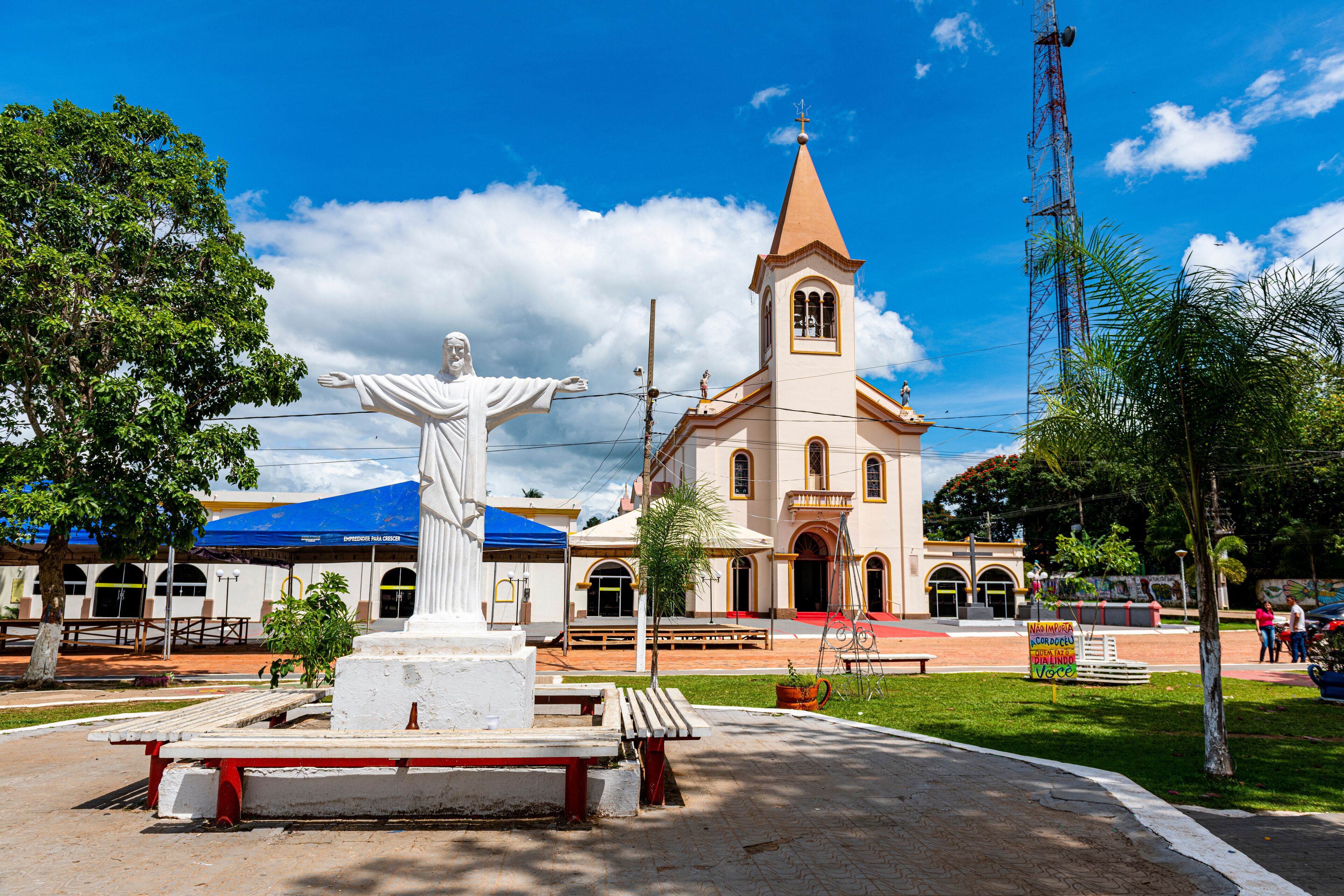 A statue of Jesus Christ, a church, and a blue-roofed building.