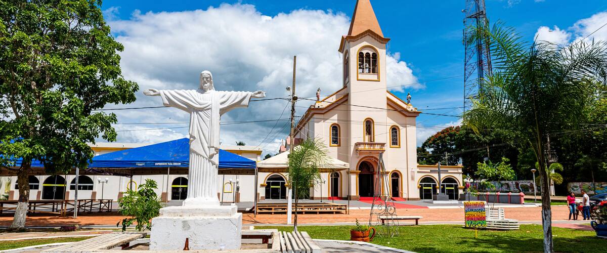 A statue of Jesus Christ, a church, and a blue-roofed building.