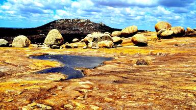 Lajedo do Pai Matheus is a mystic and secluded area in the Northeast high desert. From the top plateau you can see the lasgest monolites sculped by nature and the small lakes formed by erratic rainfalls, which also paint the soil and the rocks with amazing yellow, brown and vivid orange, due the action of minerals and oxidation.