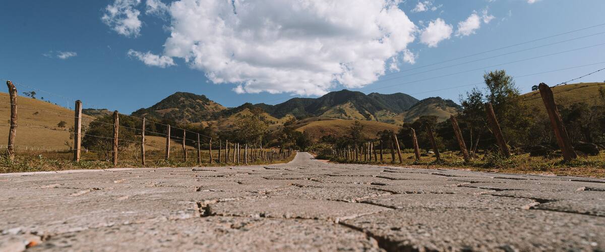A cracked road with mountains in the background and a clear sky.
