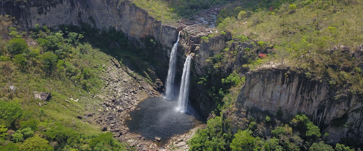 A waterfall cascading down a rocky gorge surrounded by lush greenery.