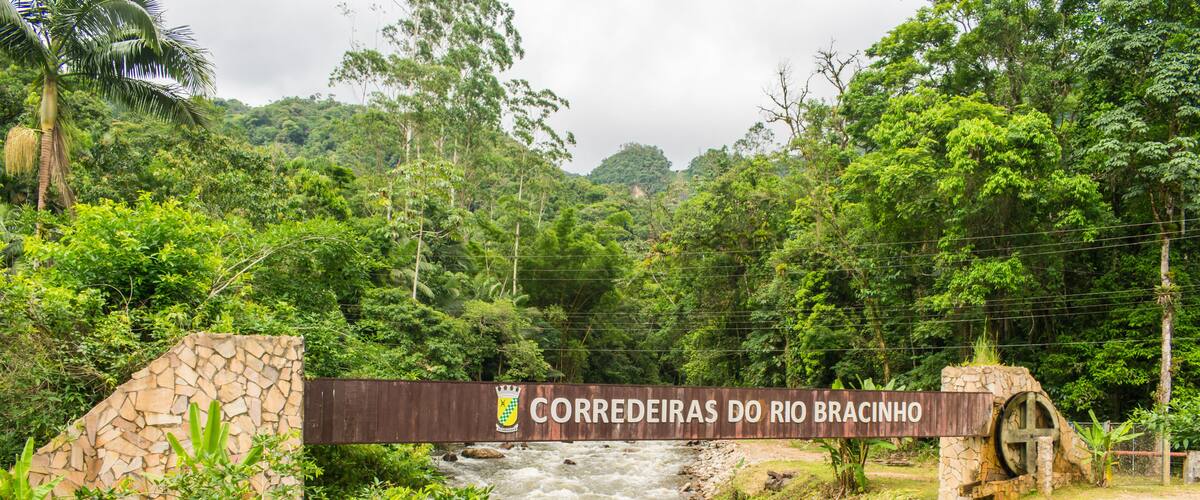 A river flowing under a bridge with a sign that reads "CORREDEIRAS DO RIO BRACINHO".