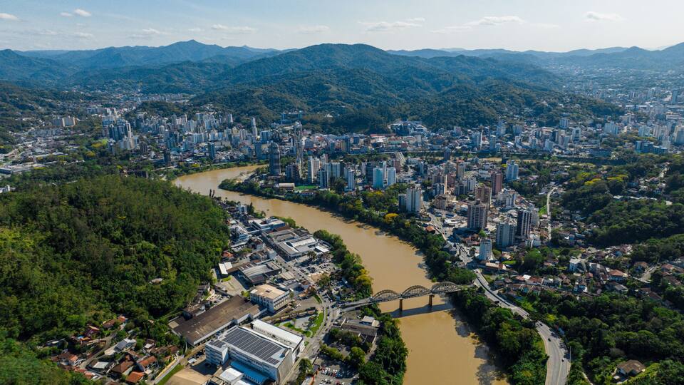 Ein Fluss fließt durch eine Stadt, im Hintergrund sind Berge zu sehen.