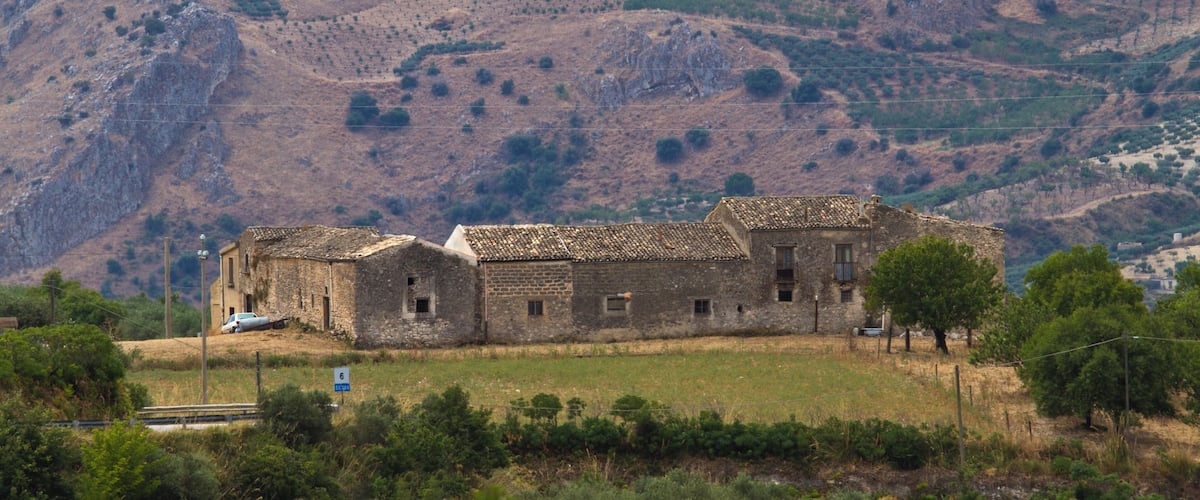 A rural village with stone houses surrounded by a hilly landscape.