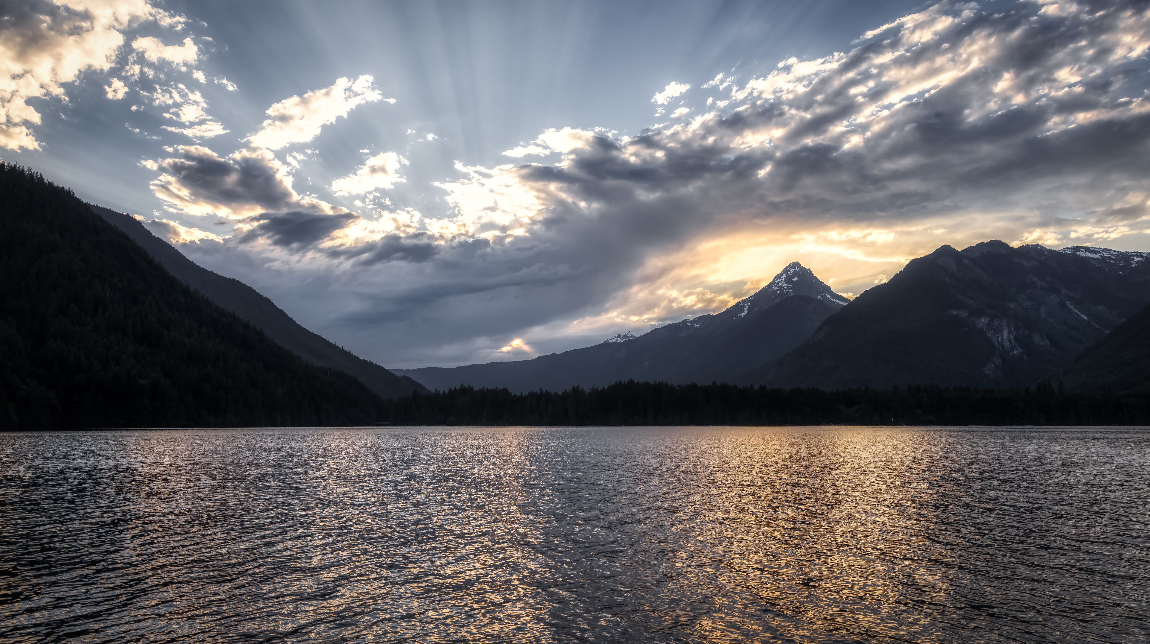 Une chaîne de montagnes, un lac et un ciel nuageux.