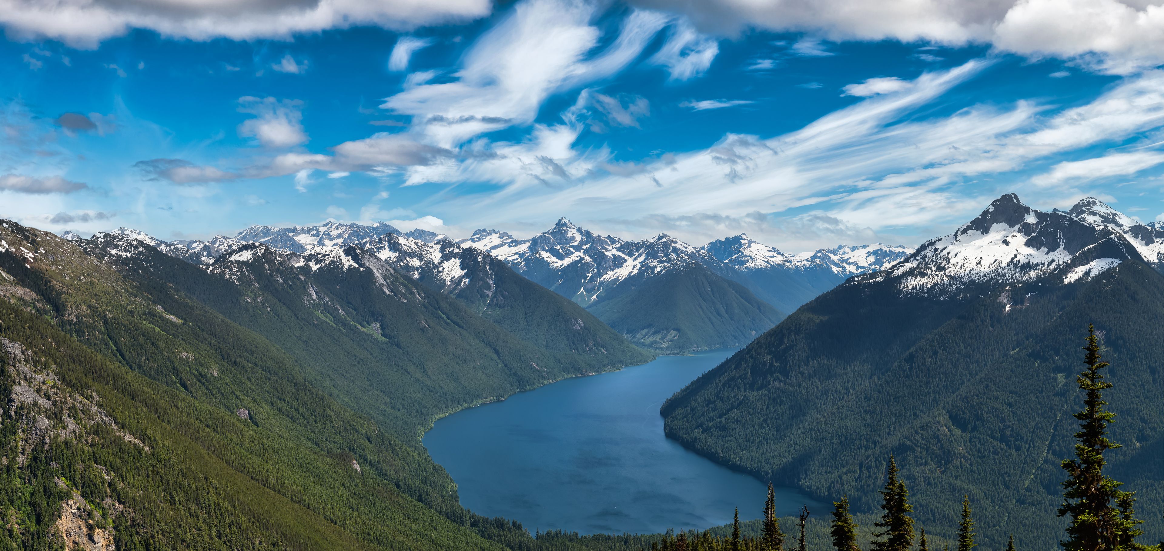 Un paysage montagneux avec un lac et des sommets enneigés.