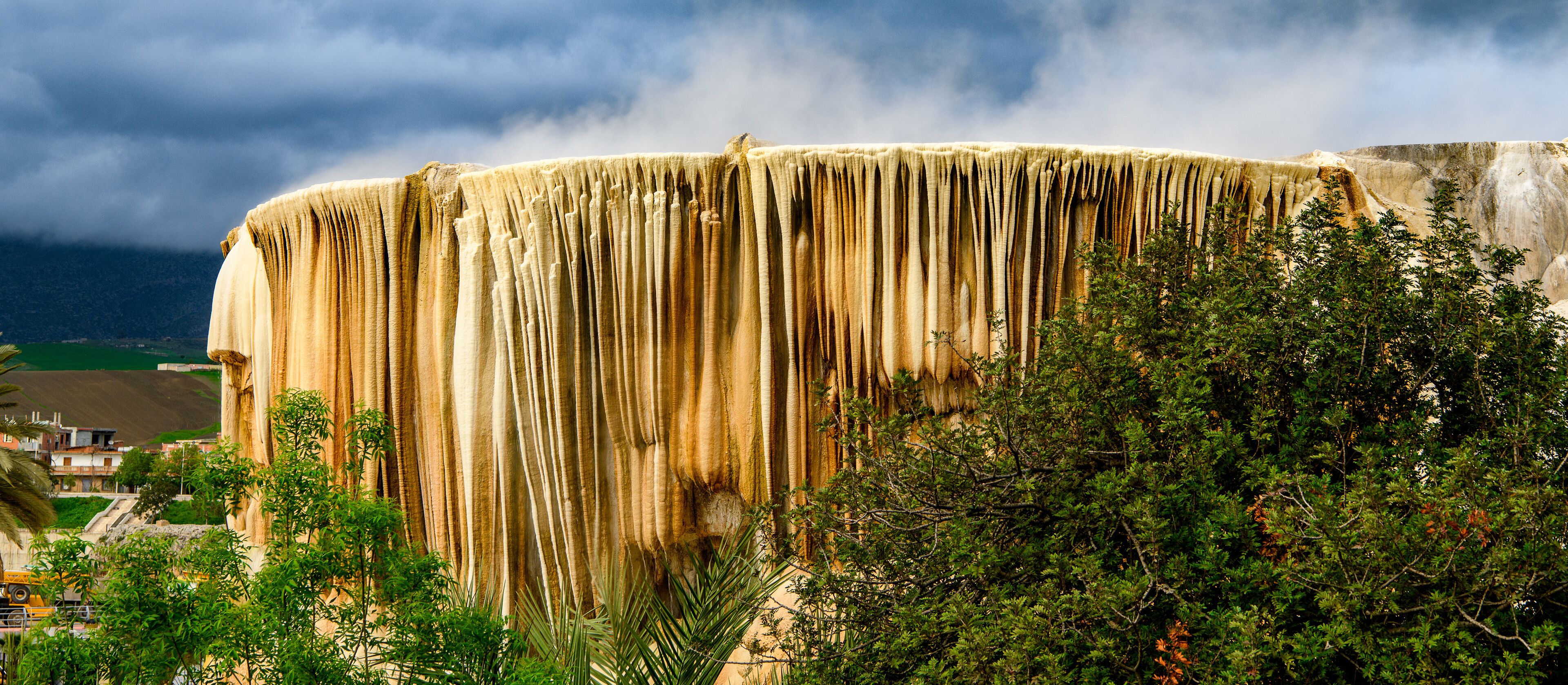 A large, vertical rock formation with a rough texture and a series of vertical grooves.