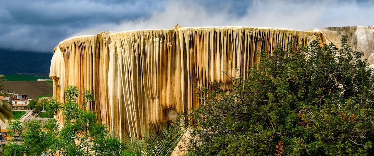 A large, vertical rock formation with a rough texture and a series of vertical grooves.
