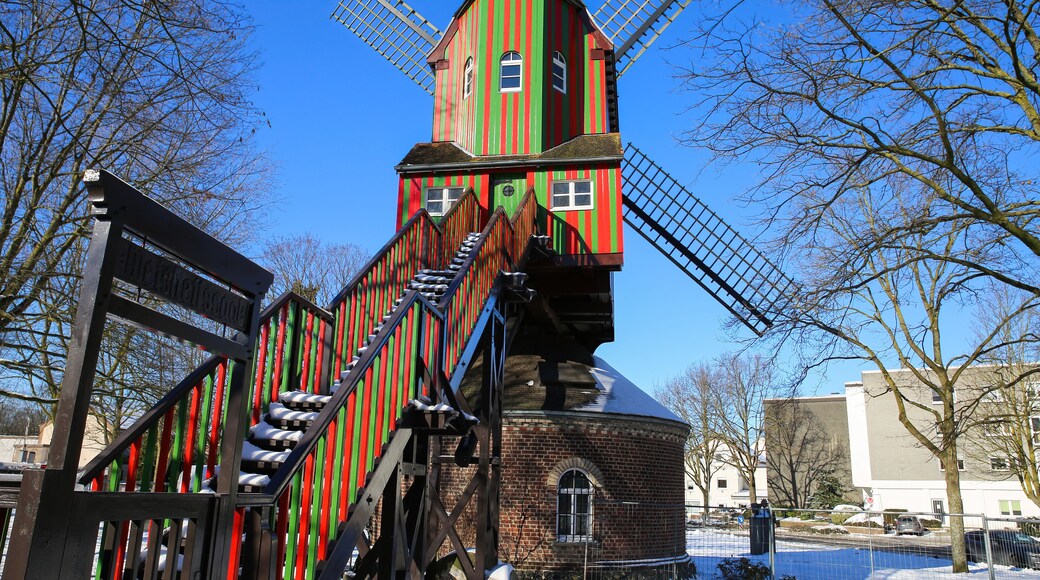 Viersen (Dulken), Germany - February 9. 2021: View beyond steps on red green colorfull striped wind mill (Narrenmuhle) against blue sky in winter