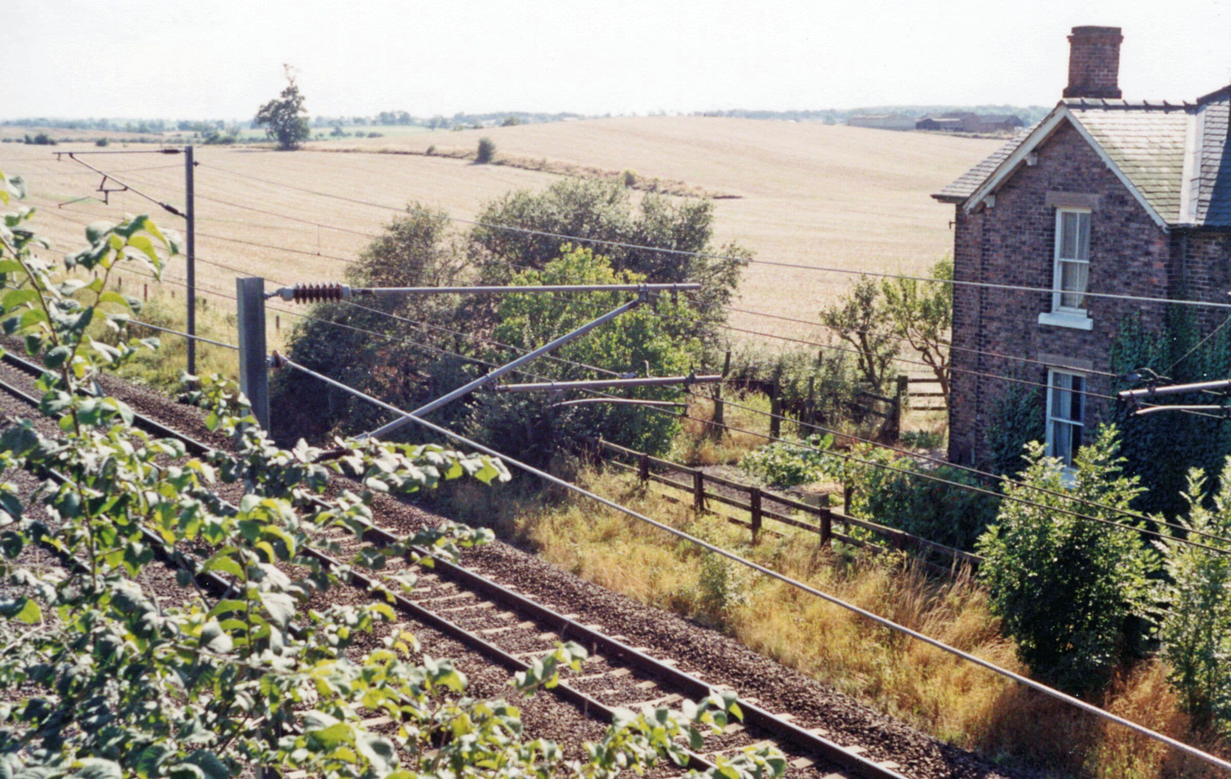 Site of Danby Wiske station, ECML 1991. View southward, towards Northallerton, York etc.: ex-NER section of the East Coast Main Line, electrified 1989. The small wayside station was closed 15/9/58. The house on the right may have been the station house.