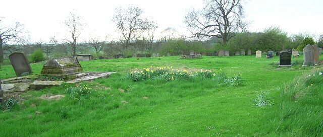 A cemetery with headstones and tombs in a grassy field.