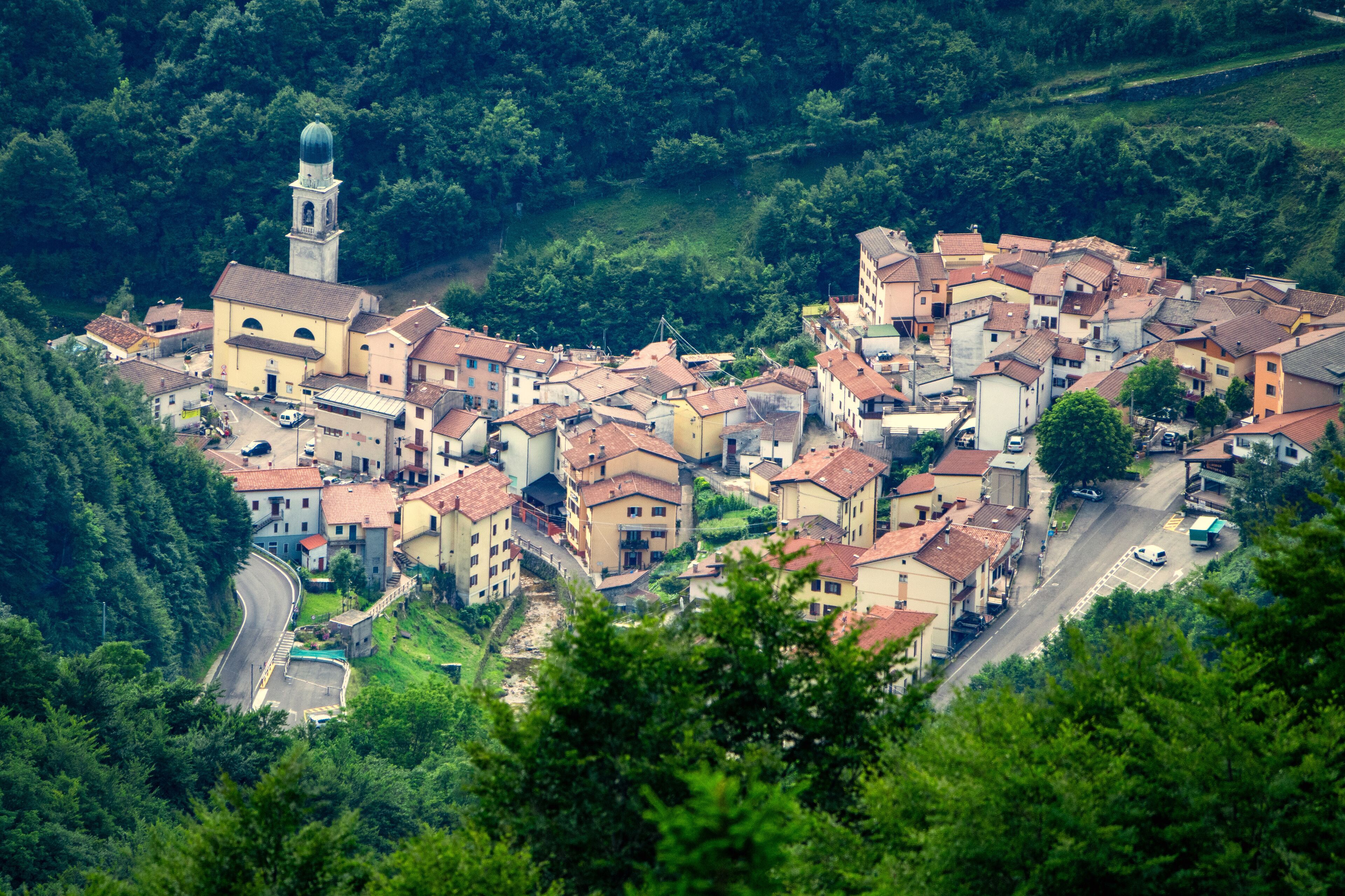A hillside village with a prominent church tower, terraced houses, and lush greenery.