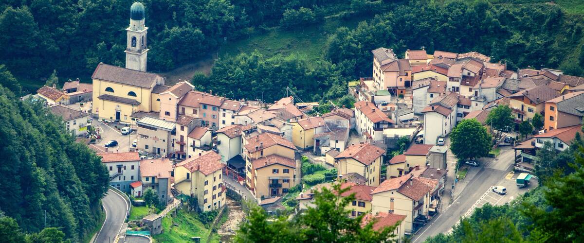 A hillside village with a prominent church tower, terraced houses, and lush greenery.