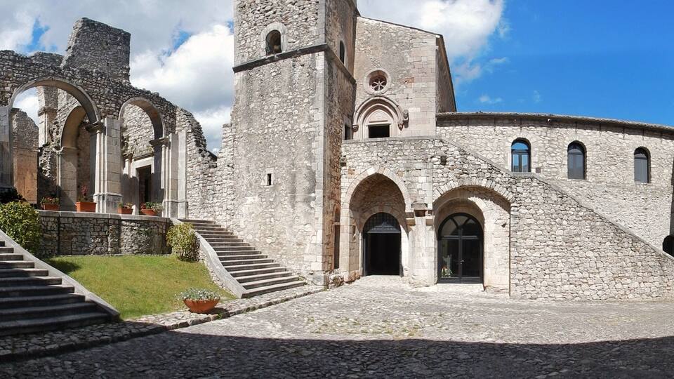 An ancient stone building with arched doorways and a central tower.